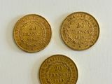 three gold coins sitting on top of a white surface