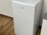 a small white refrigerator next to a small white trash can