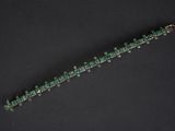 a close up of a green beaded bracelet on a black surface