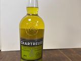 un gros plan sur une bouteille de Chartreuse posée sur une table en bois