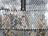 a close up of a silver sequinned jacket with a zipper