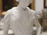a white statue of a woman holding a basket of flowers