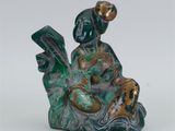 une image représentant une figurine d'une femme assise sur un rocher, en train de lire un livre