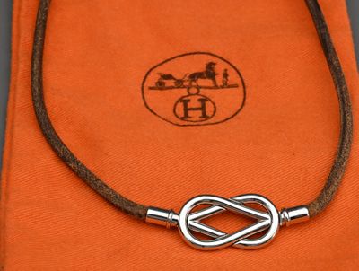 une photo d'un collier orné d'un nœud, posé sur un tissu orange