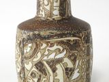 un vase brun et blanc posé sur une surface blanche