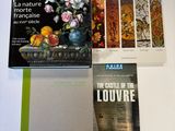trois livres posés sur une table sur laquelle se trouve un vase de fleurs