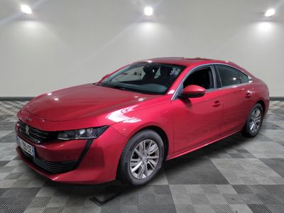 une voiture rouge est garée dans une pièce au sol en damier