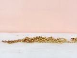 a gold chain bracelet with a tiny bead on it