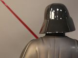 darth vader with a red light saber standing in front of a darth vader statue