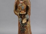 une image représentant une statue de femme tenant des fleurs, posée sur un socle en bois