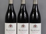 three bottles of red wine sitting on top of a table