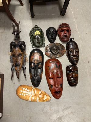 de nombreux masques en bois éparpillés sur le sol d'une pièce
