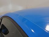 a close up of a blue car parked in a parking lot