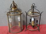 une paire de lanternes anciennes en laiton et en verre posées sur une table rouge