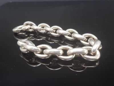 un gros plan d'un bracelet à chaîne argentée posé sur une surface noire