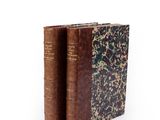 two old books sitting on top of each other on a white surface