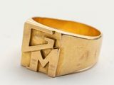 un gros plan d'une bague en or sur laquelle figure la lettre « m »
