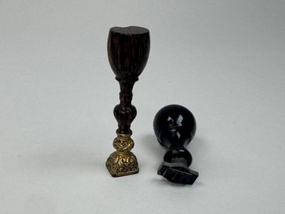 une bougie noire et un bougeoir doré placés l'un à côté de l'autre