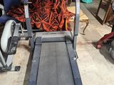 un gros plan sur un tapis de course dans un garage, avec une chaise en arrière-plan