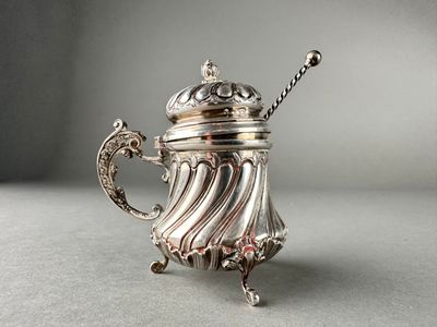 an antique silver teapot with a handle on a table