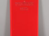 a red book sitting on top of a table next to a white wall