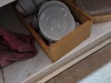 a wooden box with dishes inside of it on the floor