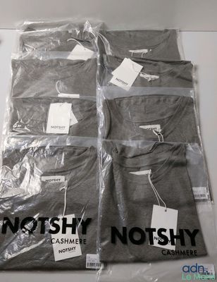 three men ' s t - shirts wrapped in plastic on a table
