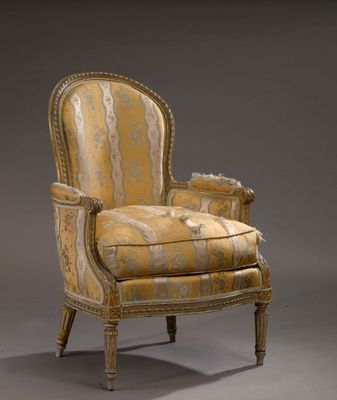 un fauteuil rembourré dont le dossier est recouvert d'un tissu doré et blanc