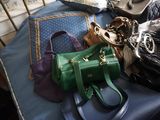 de nombreux sacs et sacs à main posés sur un lit, avec une chaise en arrière-plan