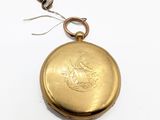 an old gold pocket watch with a key on a white surface