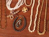 many different types of necklaces and bracelets on a table