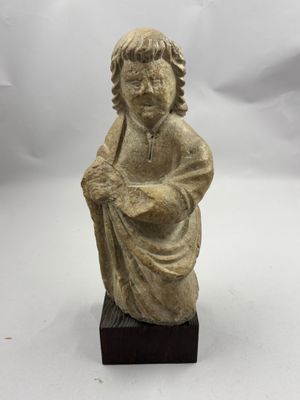 une petite statue représentant un garçon tenant un oiseau, posée sur un socle en bois