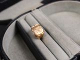 une montre en or posée dans un écrin contenant également une bague
