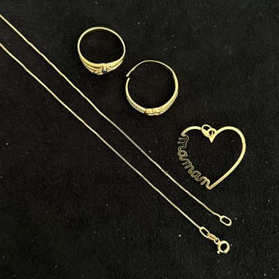 two gold rings and a necklace on a black surface