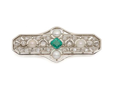 un gros plan sur une broche ornée de perles et d'émeraudes