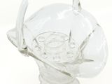 a clear glass vase with a handle on a white surface