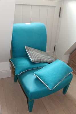 une chaise bleue sur laquelle est posé un coussin, dans un coin de la pièce