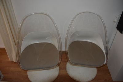une paire de chaises en plastique transparent posées sur un parquet en bois massif