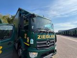 two green trucks parked next to each other on the side of the road