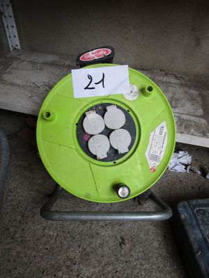 un souffleur vert posé par terre à côté d'une boîte à outils