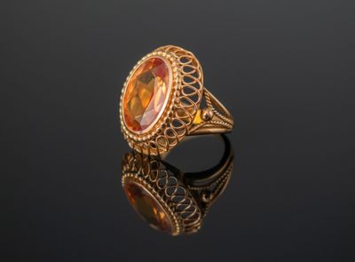 un gros plan d'une bague en or sertie d'une pierre orange