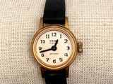 a gold wrist watch with a black band on it
