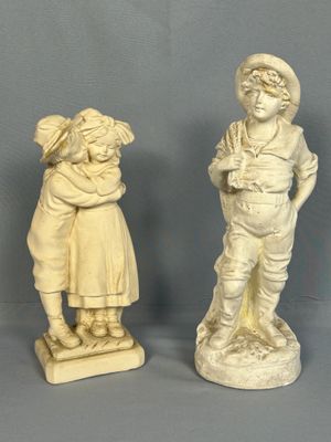 deux statues représentant un garçon et une fille debout l'un à côté de l'autre