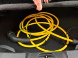 a person holding a yellow hose in the trunk of a car