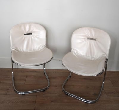 deux chaises blanches placées l'une à côté de l'autre sur un parquet en bois massif