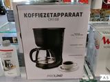 une boîte sur laquelle est posée une cafetière, exposée en vitrine