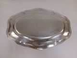 un plat ancien en argent posé sur une table blanche, sur fond blanc