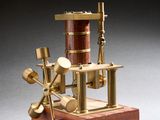 une petite maquette de machine à vapeur posée sur un socle en bois