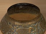a metal bowl with a design on it sitting on a table