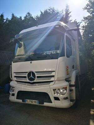 un camion blanc garé devant des arbres